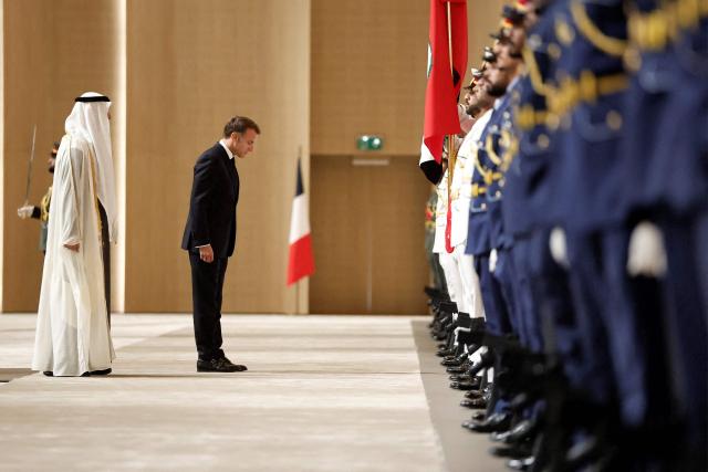 UAE President Sheikh Mohamed bin Zayed Al-Nahyan (L) and France's President Emmanuel Macron (C) inspect an honour guard during a reception ceremony at Abu Dhabi International Airport in Abu Dhabi on October 19, 2026. Macron began a Gulf tour on October 19 aimed at securing oil and diesel supplies in an effort to bring down prices, after a weekend of violent protests sparked by soaring living costs. (Photo by Benoit Tessier / POOL / AFP)