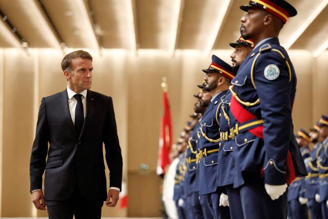 France's President Emmanuel Macron inspects an honour guard during a reception ceremony at Abu Dhabi International Airport in Abu Dhabi on October 19, 2026. Macron began a Gulf tour on October 19 aimed at securing oil and diesel supplies in an effort to bring down prices, after a weekend of violent protests sparked by soaring living costs. (Photo by Benoit Tessier / POOL / AFP)