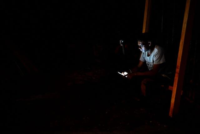A man uses his mobile phone in Colombo on October 19, 2026 during a power outage as part of Sri Lanka's electricity rationing measure, two days after a nationwide blackout. Sri Lanka announced nationwide electricity rationing from October 19, two days after a complete breakdown of the national grid caused by a fault at a coal-fired generator. The state-run electricity utility said power would be cut for one hour in stages across the island during a four-hour period from October 19 evening. (Photo by Ishara S. KODIKARA / AFP)