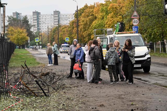Children stand by a missile crater near a school damaged following a Russian ballistic missile attack in Kyiv on October 19, 2026, amid the Russian invasion of Ukraine. (Photo by Sergei SUPINSKY / AFP)