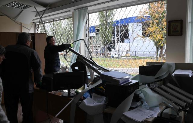 A teacher removes a broken window at a school damaged following a Russia's ballistic missile attack in Kyiv on 19 October 2026, amid the Russia's invasion of Ukraine. (Photo by Sergei SUPINSKY / AFP)