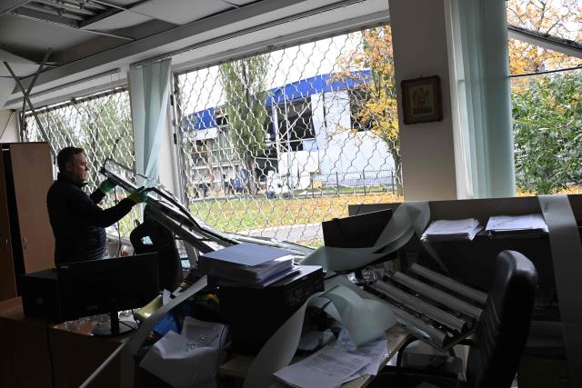 A teacher removes a broken window at a school damaged following a Russia's ballistic missile attack in Kyiv on 19 October 2026, amid the Russia's invasion of Ukraine. (Photo by Sergei SUPINSKY / AFP)