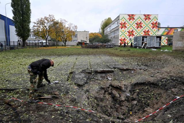 An expert examines a crater near a school damaged following a Russian ballistic missile attack in Kyiv on October 19, 2026, amid the Russian invasion of Ukraine. (Photo by Sergei SUPINSKY / AFP)