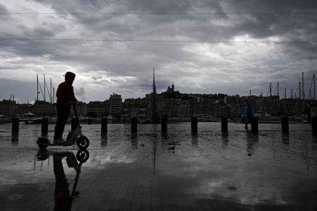 A man rides an e-scooter in the rain at Vieux Port in Marseille, southern France, on October 19, 2026. (Photo by Justine Meddah / AFP)