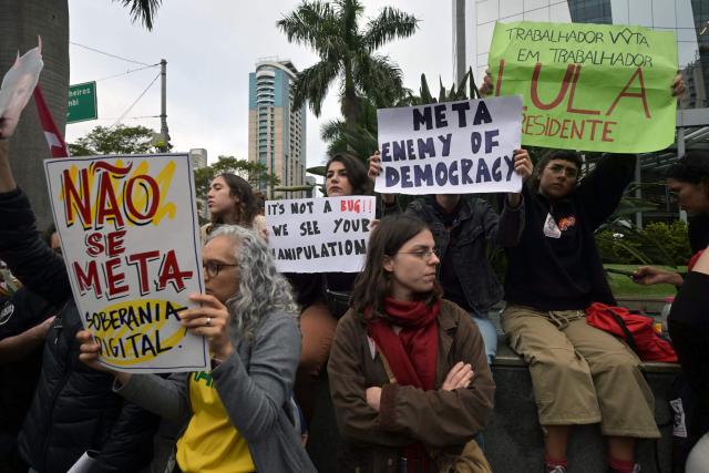 Supporters of Brazil's President and presidential candidate Luiz Inacio Lula da Silva hold placards reading "Meta Enemy of Democracy", "It's Not a Bug!! We See Your Manipulation", "No to Meta" and "Worker Votes for Worker, Lula President" during a demonstration in front of Meta's headquarters in Sao Paulo, Brazil, on October 19, 2026, denouncing alleged interference by big tech companies in the Brazilian election. Brazil's electoral court on October 19, 2026 gave Meta 24 hours to show that it is taking measures to ensure equal treatment on its platforms for the campaigns of Luiz Inacio Lula da Silva and Flavio Bolsonaro, less than a week before the presidential runoff election. (Photo by NELSON ALMEIDA / AFP)