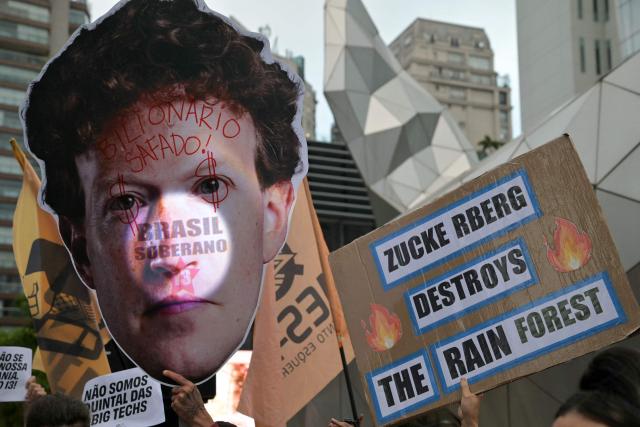 Supporters of Brazil's President and presidential candidate Luiz Inacio Lula da Silva hold a large cutout depicting Meta chief executive Mark Zuckerberg reading "Billionaire Outdated!" and "Sovereign Brazil" and a placard reading "Zuckerberg Destroys the Rain Forest" during a demonstration in front of Meta's headquarters in Sao Paulo, Brazil, on October 19, 2026, denouncing alleged interference by big tech companies in the Brazilian election. Brazil's electoral court on October 19, 2026 gave Meta 24 hours to show that it is taking measures to ensure equal treatment on its platforms for the campaigns of Luiz Inacio Lula da Silva and Flavio Bolsonaro, less than a week before the presidential runoff election. (Photo by NELSON ALMEIDA / AFP)