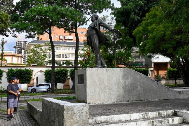 People walk past the monument honoring Nobel Prize-winning author Miguel Angel Asturias in Guatemala City on October 19, 2026. Guatemala marks the anniversary of his birth on October 19, 1899. (Photo by Johan ORDONEZ / AFP)