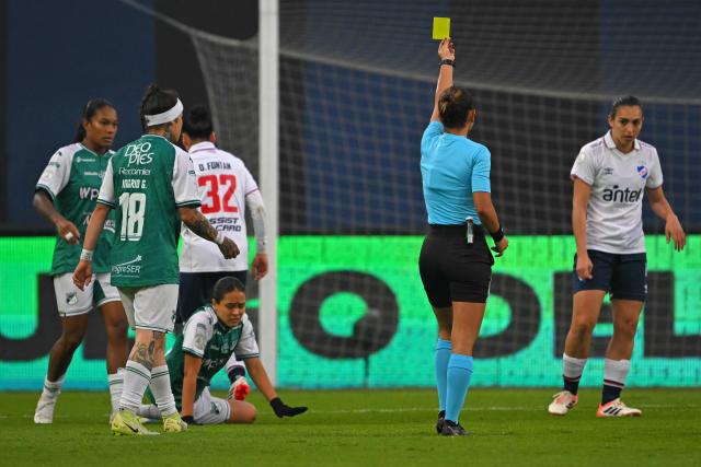 Brazilian referee Daiane Caroline Muniz shows a yellow card to Nacional's defender #04 Pierina Gonzalez (R) during the 2026 Women's Copa Libertadores Group D football match between Colombia's Deportivo Cali and Uruguay's Nacional at the Banco Guayaquil Stadium in Quito on October 19, 2026. (Photo by Rodrigo BUENDIA / AFP)