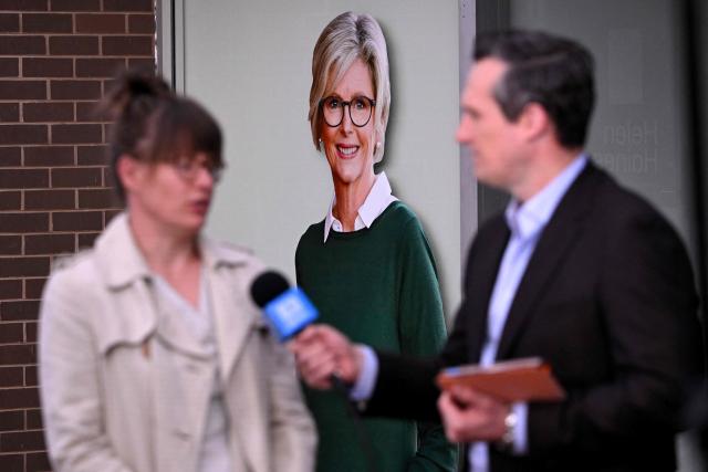 A TV crew works in front of a portrait of Australian politician Helen Haines (C) outside her office in the northern regional city of Wangaratta, about 250 kilometres north-east of Melbourne on October 20, 2026. Australian independent lawmaker Helen Haines underwent surgery overnight but remains in a critical condition after being struck deliberately by a car in an attack, Prime Minister Anthony Albanese said on October 20. Political violence is rare in Australia, but law enforcement have documented a steady rise in threats and abuse directed towards the nation's elected officials in recent years. (Photo by William WEST / AFP)