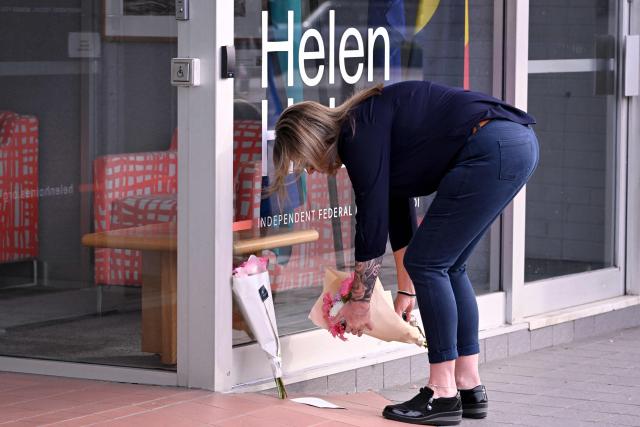 A woman places flower outside the office of Australian politician Helen Haines in the northern regional city of Wangaratta, about 250 kilometres north-east of Melbourne on October 20, 2026. Australian independent lawmaker Helen Haines underwent surgery overnight but remains in a critical condition after being struck deliberately by a car in an attack, Prime Minister Anthony Albanese said on October 20. Political violence is rare in Australia, but law enforcement have documented a steady rise in threats and abuse directed towards the nation's elected officials in recent years. (Photo by William WEST / AFP)