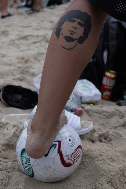 A Boca Juniors fan displays a tattoo depicting legendary former footballer Diego Armando Maradona during a gathering know as "Banderazo" at Copacabana Beach in Rio de Janeiro, Brazil, on October 19, 2026, ahead of the Copa Sudamericana semi-final second leg football match between Brazil's Vasco da Gama and Argentina's Boca Juniors. (Photo by Pablo PORCIUNCULA / AFP)
