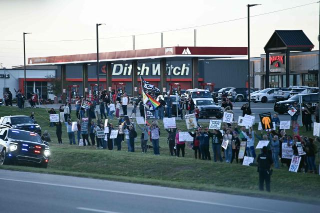 Anti-Trump protestors hold up signs as US President Donald Trump travels to speak at a campaign rally in Park City, Kansas, on October 19, 2026. (Photo by Kent NISHIMURA / AFP)