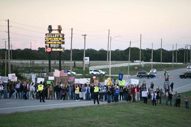 Anti-Trump protestors hold up signs as US President Donald Trump travels to speak at a campaign rally in Park City, Kansas, on October 19, 2026. (Photo by Kent NISHIMURA / AFP)
