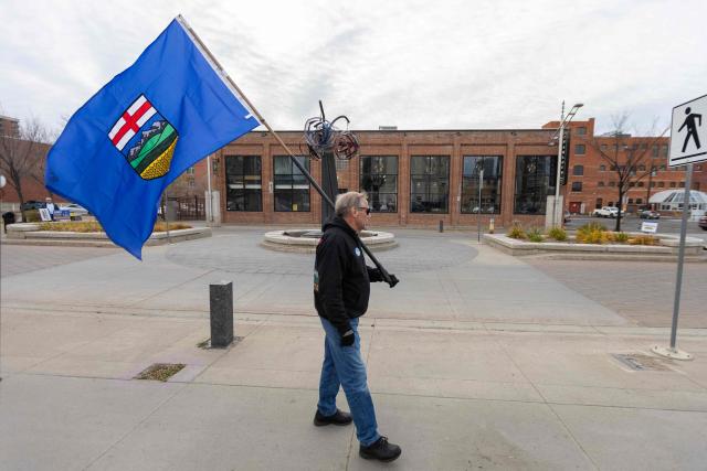An Alberta separatist supporter carries a flag ahead of the referendum in downtown Edmonton, Alberta, on October 19, 2026. Alberta votes today to determine if it wants to pursue a binding referendum on leaving Canada, with Prime Minister Mark Carney warning a separatist win would bring dangerous uncertainty during a trade war with the United States. Polls indicate less than a quarter of people in the western Canadian province support independence. (Photo by Megan Albu / AFP)