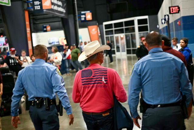 A protestor is escorted out of a campaign rally with US President Donald Trump at the Heartland Credit Union Arena in Park City, Kansas, a suburb of Wichita, on October 19, 2026. (Photo by Kent NISHIMURA / AFP)