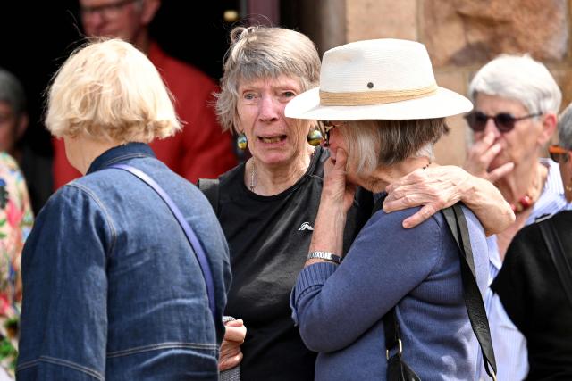 People embrace after a vigil for Australian politician Helen Haines at the Holy Trinity Cathedral in the northern regional city of Wangaratta, some 250 kilometres north-east of Melbourne on October 20, 2026. Australian lawmaker Helen Haines has lost a leg after being struck by a car in a deliberate attack, local media said October 20. (Photo by William WEST / AFP)