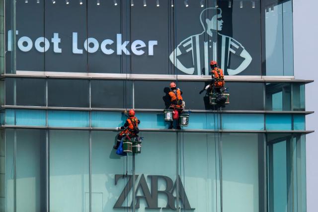 Workers clean the exterior glass facade of a shopping mall in Jakarta on October 20, 2026. (Photo by BAY ISMOYO / AFP)