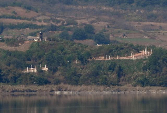 A North Korean guard post and military fences on the North side of the Demilitarised Zone (DMZ) dividing the two Koreas, are seen from a South Korean observatory in the border city of Paju on October 20, 2026. South Korea's military warned October 20, of a "firm" response and resolute punishment for any further provocations by North Korea, saying it was "unacceptable" for Pyongyang to blame Seoul for escalating tensions. (Photo by Jung Yeon-je / AFP)