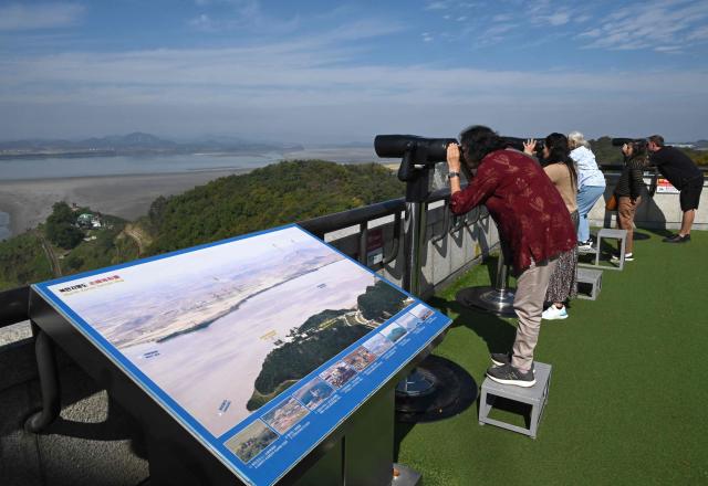 Visitors use binoculars to look at the North Korean side of the Demilitarised Zone (DMZ) dividing the two Koreas, from a South Korean observatory in the border city of Paju on October 20, 2026. South Korea's military warned October 20, of a "firm" response and resolute punishment for any further provocations by North Korea, saying it was "unacceptable" for Pyongyang to blame Seoul for escalating tensions. (Photo by Jung Yeon-je / AFP)