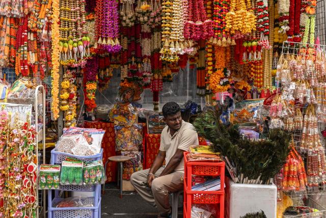 A vendor waits for customers at a temporary stall selling decorative items for the upcoming Hindu festival of Diwali in the Little India district in Singapore on October 20, 2026. (Photo by Roslan RAHMAN / AFP)