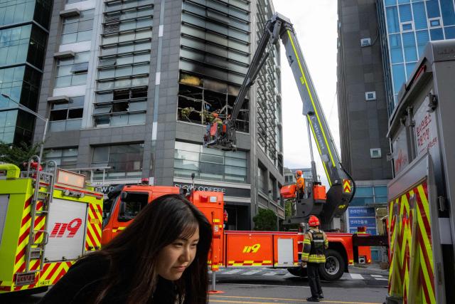 Firefighters work at the scene of a fire at a building in the Gangnam district in Seoul on October 20, 2026. (Photo by Philip FONG / AFP)
