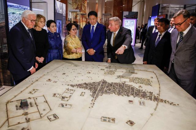 German President Frank-Walter Steinmeier (L), his wife Elke Buedenbender (2ndL), Mongolia's President Ukhnaagiin Khurelsukh (5thL) and the  Director General of the Berlin State Library (SPK) Professor Dr. Achim Bonte (R) listen to explanations by the director of the Museum of Prehistory and Early History at the National Museums in Berlin (SPK) Professor Dr. Matthias Wemhoff (6thL) as they look at a model during their visit of the exhibition „Dschingis Khan und die Welt der Mongolen“ (“Genghis Khan and the World of the Mongols”) at the James-Simon-Galerie museim in Berlin on October 20, 2026. Mongolia's President is on a three-day State visit in Germany. The exhibition has been organized to mark the 800th anniversary of the death of Genghis Khan, the founder of the Mongolian empire in 2027. (Photo by Axel Schmidt / POOL / AFP)