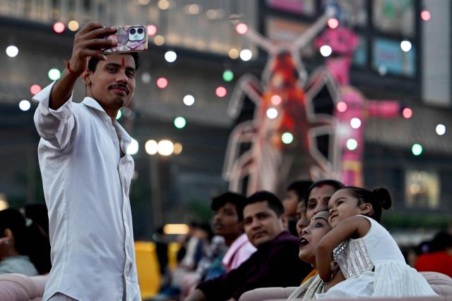People gathered to watch a 'Ramleela' performance take pictures near a cockroach effigy, due to be burnt alongside an effigy of the mythic demon king Ravana on the occasion of the Hindu festival of Dussehra in New Delhi on October 20, 2026, amid youth-led Cockroach Janta Party (CJP) protests demanding the resignation of India's Chief Election Commissioner Gyanesh Kumar over alleged voter roll irregularities linked to the "special intensive revision" (SIR). (Photo by Arun SANKAR / AFP)