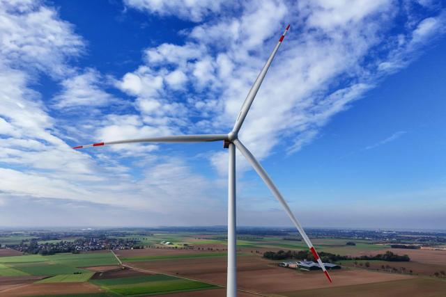 An aerial view shows a wind turbine near the western German opencast mining region at Erkelenz-Holzweiler, western Germany on October 20, 2026. Two new wind turbines at the Erkelenz-Holzweiler wind farm, located on the edge of the Garzweiler II open-pit mine, were officially commissioned today. With a total height of approximately 250 meters each and a capacity of 7.2 megawatts each, they are the tallest wind turbines in the Heinsberg district. (Photo by Ina FASSBENDER / AFP)