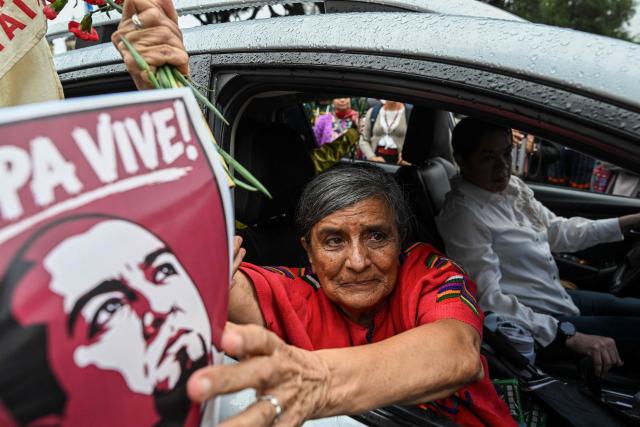 Silvia Solorzano, mother of lawyer Francisco Solorzano Foppa, holds a poster bearing her son's portrait after a posthumous tribute at Constitution Square in Guatemala City on October 20, 2026. A former Guatemalan prosecutor who denounced corruption cases and alleged links between gangs and politicians was shot dead in Guatemala City on October 17, 2026, police said. Lawyer Juan Francisco Solorzano Foppa was attacked at a football field he frequented on weekends, according to a police report, which said two suspected perpetrators had been detained on a preliminary basis. (Photo by Johan ORDONEZ / AFP)