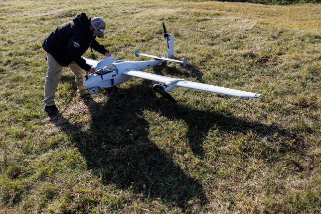 An employee is preparing to launch a ‘Reliant’ reconnaissance and surveillance drone of the German drone producer Quantum Systems at a training area, Central Germany on October 20, 2026. As part of its Multi-Domain Operations Exercise, the company is showcasing its latest developments. Quantum Systems and selected industry partners are set to conduct a series of live demonstrations illustrating how autonomous air, land and sea systems work together under realistic operational conditions. (Photo by Jens SCHLЬTER / AFP)