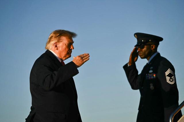 US President Donald Trump returns a salute as he boards Air Force One at Joint Base Andrews in Maryland, on October 20, 2026. President Trump is travelling to North Carolina to support Republican candidates. (Photo by Kent NISHIMURA / AFP)