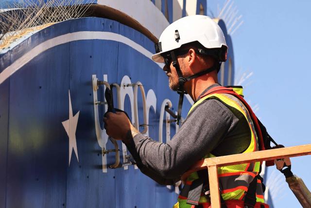 A worker removes the Santa Monica Pier sign at the end of Route 66 in Santa Monica, California, on October 20, 2026. The landmark Santa Monica Pier sign will begin coming down Tuesday for restoration in Las Vegas as part of a project to replace the aging bridge connecting Ocean Avenue to the pier, city officials announced. The sign is listed on the California Register of Historical Resources and is expected to return to the pier entrance when construction of the new bridge is completed in 2028, according to the city. (Photo by David Swanson / AFP)