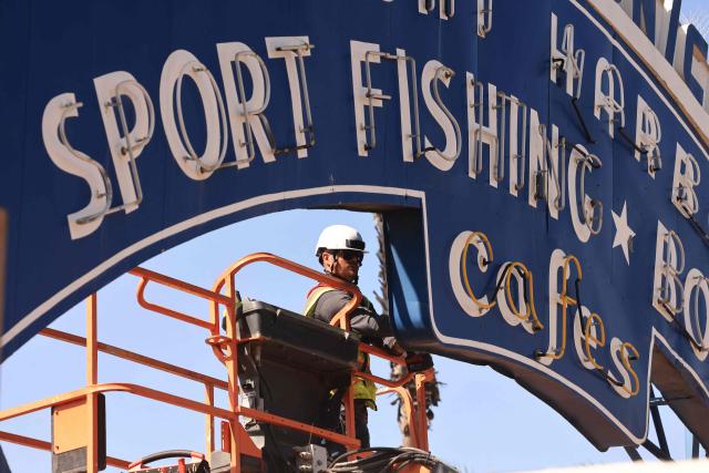 A worker removes the Santa Monica Pier sign at the end of Route 66 in Santa Monica, California, on October 20, 2026. The landmark Santa Monica Pier sign will begin coming down Tuesday for restoration in Las Vegas as part of a project to replace the aging bridge connecting Ocean Avenue to the pier, city officials announced. The sign is listed on the California Register of Historical Resources and is expected to return to the pier entrance when construction of the new bridge is completed in 2028, according to the city. (Photo by David Swanson / AFP)