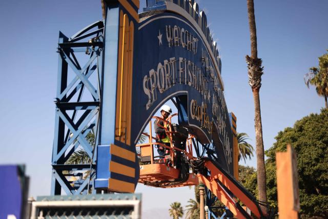A worker removes the Santa Monica Pier sign at the end of Route 66 in Santa Monica, California, on October 20, 2026. The landmark Santa Monica Pier sign will begin coming down Tuesday for restoration in Las Vegas as part of a project to replace the aging bridge connecting Ocean Avenue to the pier, city officials announced. The sign is listed on the California Register of Historical Resources and is expected to return to the pier entrance when construction of the new bridge is completed in 2028, according to the city. (Photo by David Swanson / AFP)