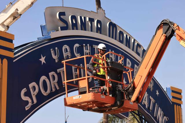 A worker removes the Santa Monica Pier sign at the end of Route 66 in Santa Monica, California, on October 20, 2026. The landmark Santa Monica Pier sign will begin coming down Tuesday for restoration in Las Vegas as part of a project to replace the aging bridge connecting Ocean Avenue to the pier, city officials announced. The sign is listed on the California Register of Historical Resources and is expected to return to the pier entrance when construction of the new bridge is completed in 2028, according to the city. (Photo by David Swanson / AFP)