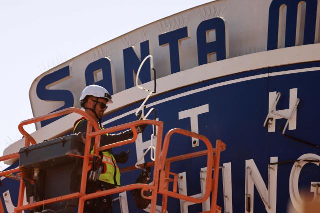 A worker removes the Santa Monica Pier sign at the end of Route 66 in Santa Monica, California, on October 20, 2026. The landmark Santa Monica Pier sign will begin coming down Tuesday for restoration in Las Vegas as part of a project to replace the aging bridge connecting Ocean Avenue to the pier, city officials announced. The sign is listed on the California Register of Historical Resources and is expected to return to the pier entrance when construction of the new bridge is completed in 2028, according to the city. (Photo by David Swanson / AFP)