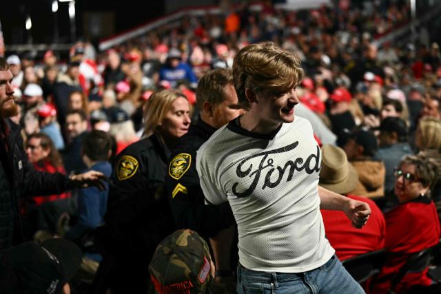 Security officers escort out a protestor as US President Donald Trump speaks at a midterm campaign rally at Pitt-Greenville Airport in Greenville, North Carolina, on October 20, 2026. (Photo by Kent NISHIMURA / AFP)