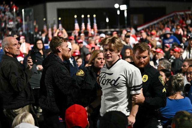 Security officers escort out a protestor as US President Donald Trump speaks at a midterm campaign rally at Pitt-Greenville Airport in Greenville, North Carolina, on October 20, 2026. (Photo by Kent NISHIMURA / AFP)