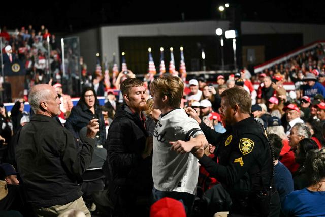 Security officers escort out a protestor as US President Donald Trump speaks at a midterm campaign rally at Pitt-Greenville Airport in Greenville, North Carolina, on October 20, 2026. (Photo by Kent NISHIMURA / AFP)