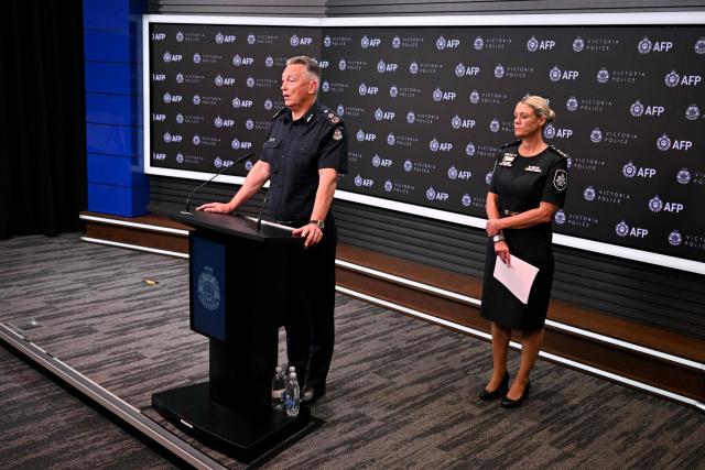 Chief Commissioner of Victoria Police Mike Bush (L) speaks alongside Commissioner of the Australian Federal Police Krissy Barrett (R) during a press conference for an update on the attack on Australian politician Helen Haines, in Melbourne on October 21, 2026. The man alleged to have critically wounded Australian lawmaker Helen Haines in a "targeted" attack appeared in court on October 21, as police warned that growing extremism online was fuelling political polarisation. (Photo by William WEST / AFP)