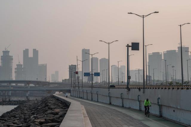 A cyclist rides along the seafront on a hazy morning in Mumbai on October 21, 2026. (Photo by Punit PARANJPE / AFP)
