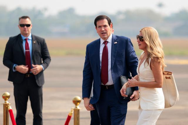 US Secretary of State Marco Rubio (C) and his wife Jeanette Dousdebes Rubio arrive to board a plane en route to Jamnagar, at  Chhatrapati Shivaji Maharaj International Airport in Mumbai on October 21, 2026. (Photo by KYLIE COOPER / POOL / AFP)