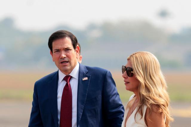 US Secretary of State Marco Rubio (L) and his wife Jeanette Dousdebes Rubio arrive to board a plane en route to Jamnagar, at  Chhatrapati Shivaji Maharaj International Airport in Mumbai on October 21, 2026. (Photo by KYLIE COOPER / POOL / AFP)