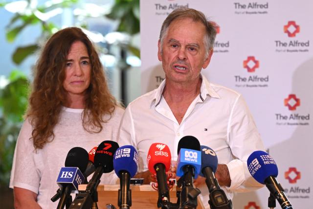 Phil Haines, husband of Australian politician Helen Haines, who lost both legs in an attack, speaks to the media with his cousin Jules Muir (L) during an update of Helen Haines' condition at the Alfred Hospital in Melbourne on October 21, 2026. Australian lawmaker Helen Haines has had both legs removed, her husband told journalists on October 21, after what police called a "targeted" attack. (Photo by William WEST / AFP)