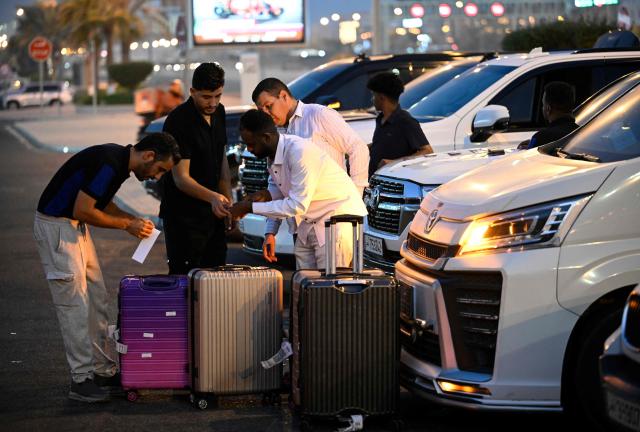 Travellers prepare to depart by road for Saudi Arabia in minibuses from Doha on October 21, 2026. Saudi Arabia has this month come under sustained attack from the Iran-backed Houthis, including a strike on Riyadh's international airport that was the kingdom's deadliest in years, as the war with the group escalates. (Photo by Mahmud HAMS / AFP)