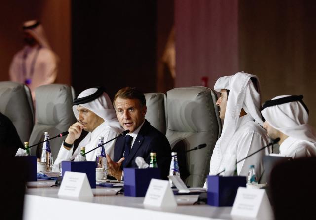 France's President Emmanuel Macron, flanked by Qatar's Prime Minister Sheikh Mohammed bin Abdulrahman al-Thani (L) and Qatar's Emir Sheikh Tamim bin Hamad al-Thani, attends the 9th Annual One Planet Sovereign Wealth Funds (OPSWF) Summit at the Rosewood Hotel in Lusail on October 21, 2026. The French president is undertaking a tour of key energy suppliers in the Gulf in an effort to secure oil and diesel and bring down prices in France. (Photo by Benoit Tessier / POOL / AFP)