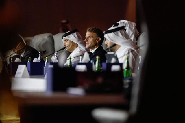 France's President Emmanuel Macron, flanked by Qatar's Prime Minister Sheikh Mohammed bin Abdulrahman al-Thani (L) and the Emir of Qatar (unseen), attends the 9th Annual One Planet Sovereign Wealth Funds (OPSWF) Summit at the Rosewood Hotel in Lusail on October 21, 2026. The French president is undertaking a tour of key energy suppliers in the Gulf in an effort to secure oil and diesel and bring down prices in France. (Photo by Benoit Tessier / POOL / AFP)