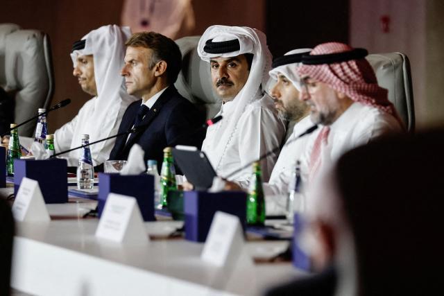 France's President Emmanuel Macron, flanked by Qatar's Prime Minister Sheikh Mohammed bin Abdulrahman al-Thani (L) and Qatar's Emir Sheikh Tamim bin Hamad al-Thani, attends the 9th Annual One Planet Sovereign Wealth Funds (OPSWF) Summit at the Rosewood Hotel in Lusail on October 21, 2026. The French president is undertaking a tour of key energy suppliers in the Gulf in an effort to secure oil and diesel and bring down prices in France. (Photo by Benoit Tessier / POOL / AFP)