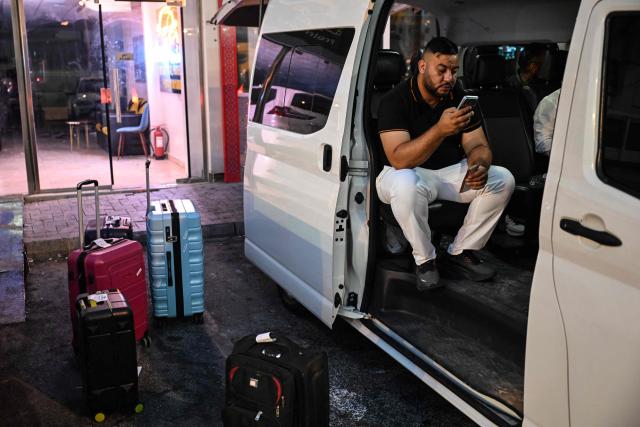 A traveller prepares to depart by road for Saudi Arabia in a minibus from Doha on October 21, 2026. Saudi Arabia has this month come under sustained attack from the Iran-backed Houthis, including a strike on Riyadh's international airport that was the kingdom's deadliest in years, as the war with the group escalates. (Photo by Mahmud HAMS / AFP)