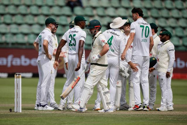 Australia's Travis Head (C) walks back to the pavilion after his dismissal by South Africa's Marco Jansen (3rd R) on day four of the second Test match between South Africa and Australia at St Georges Park in Gqeberha on October 21, 2026. (Photo by Marco Longari / AFP)